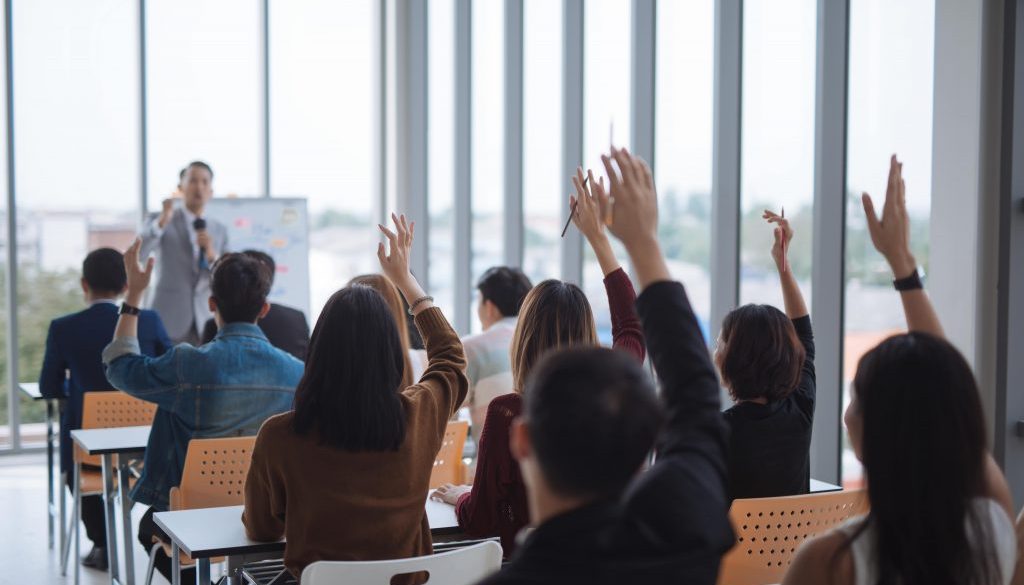 raised-up-hands-arms-large-group-seminar-class-room-agree-with-speaker-conference-seminar-meeting-room-min raised-up-hands-arms-large-group-seminar-class-room-agree-with-speaker-conference-seminar-meeting-room-min