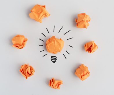 light-bulb-with-crumpled-colorful-paper-white-surface